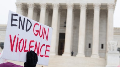 A person holds a sign reading "End Gun Violence" on the steps of the Supreme Court.