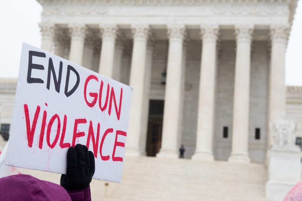 A person holds a sign reading "End Gun Violence" on the steps of the Supreme Court.