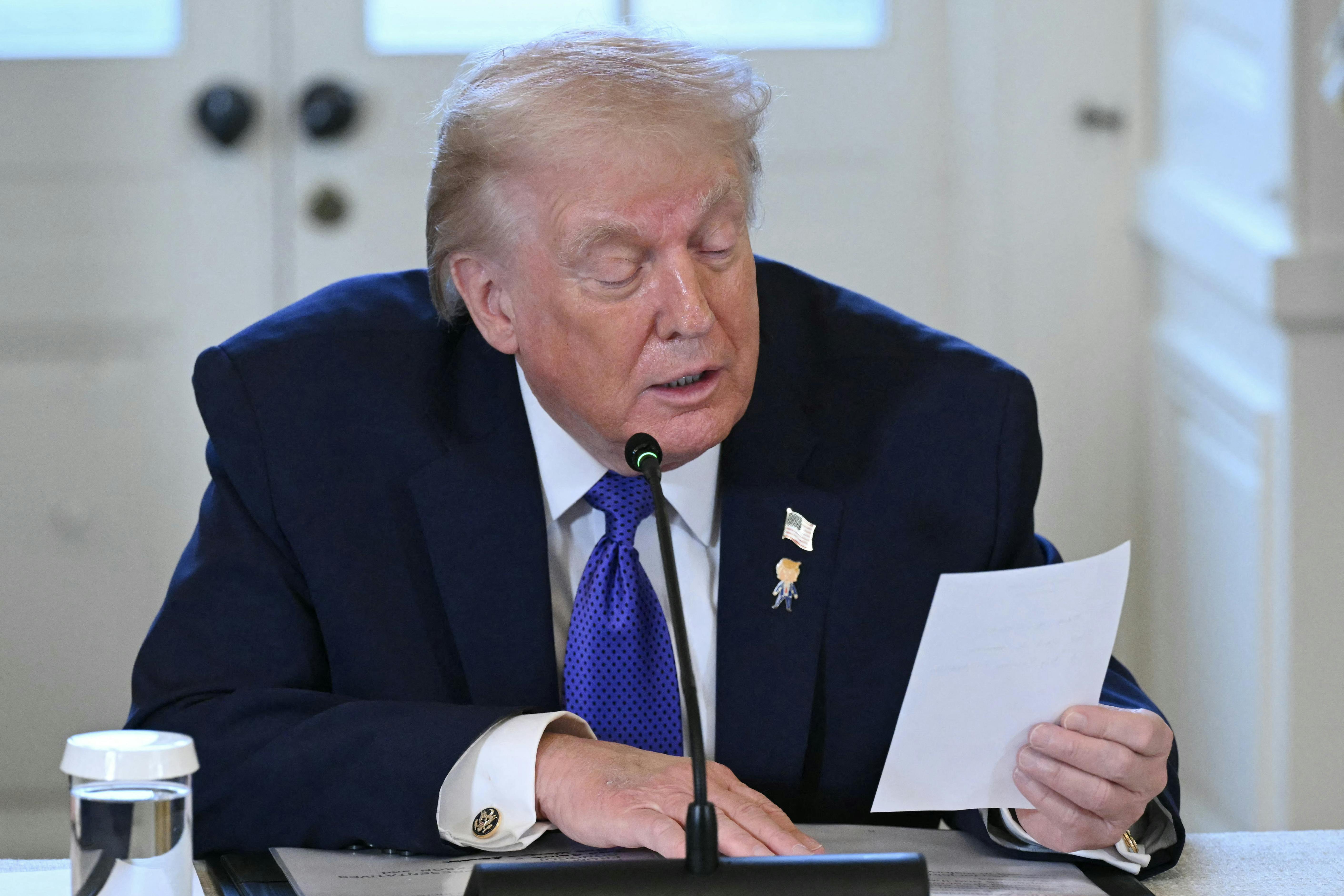 Donald Trump reads a note during a meeting with oil executives