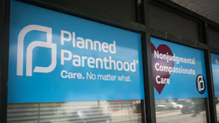 Signs hang in the window of a Planned Parenthood clinic reading "Nonjudgmental Compassionate Care" and "Care. No matter what."