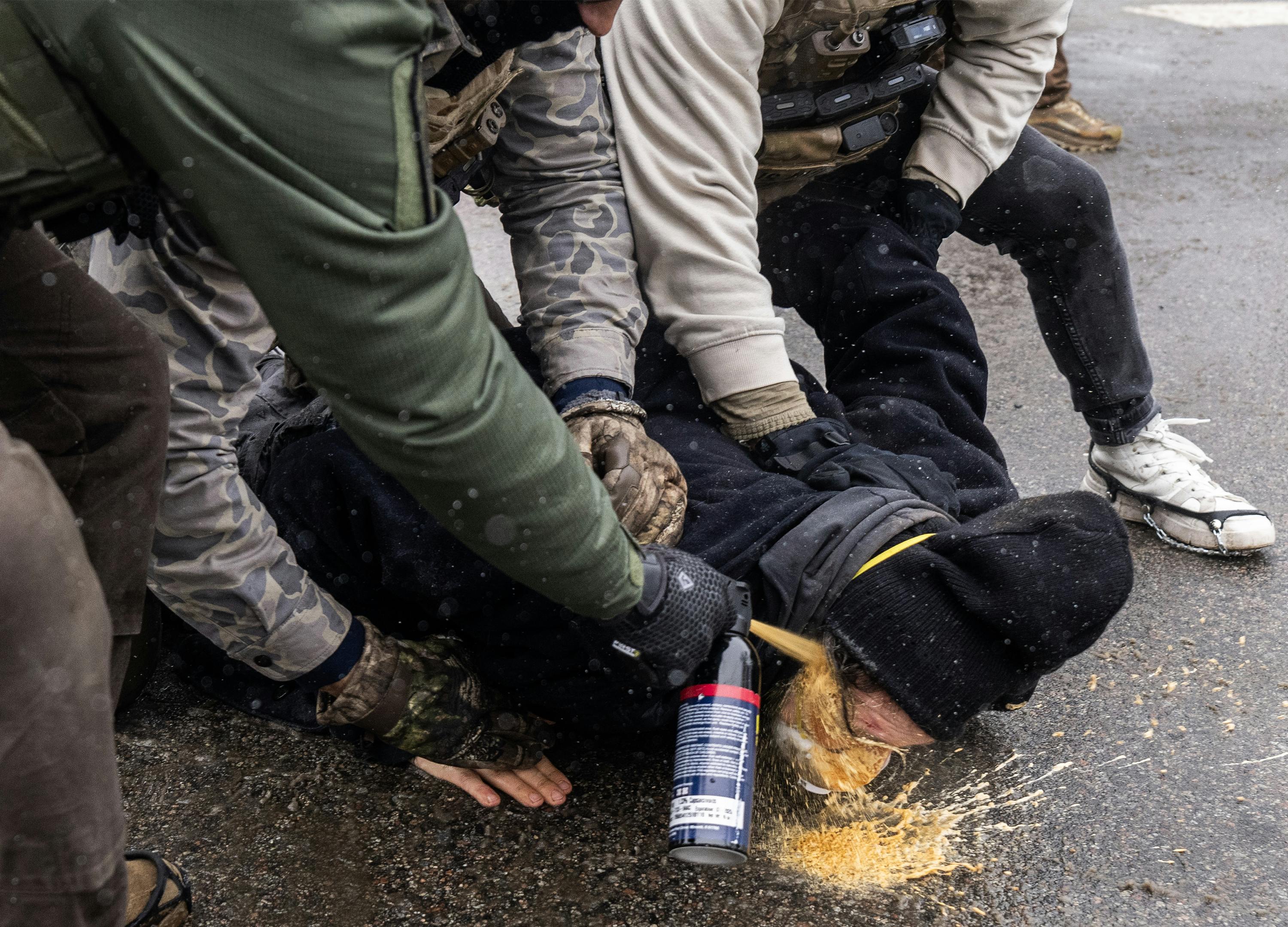 Federal immigration agents pin a protester down and spray chemical irritant directly into their eyes in Minneapolis, Minnesota