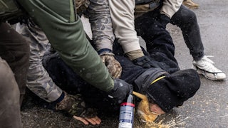 Federal immigration agents pin a protester down and spray chemical irritant directly into their eyes in Minneapolis, Minnesota