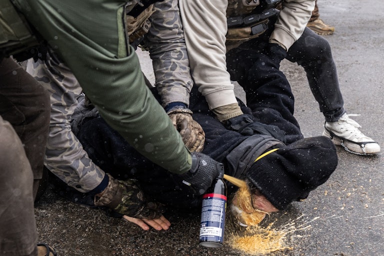 Federal immigration agents pin a protester down and spray chemical irritant directly into their eyes in Minneapolis, Minnesota