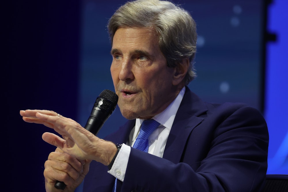 John Kerry holds a microphone and speaks.