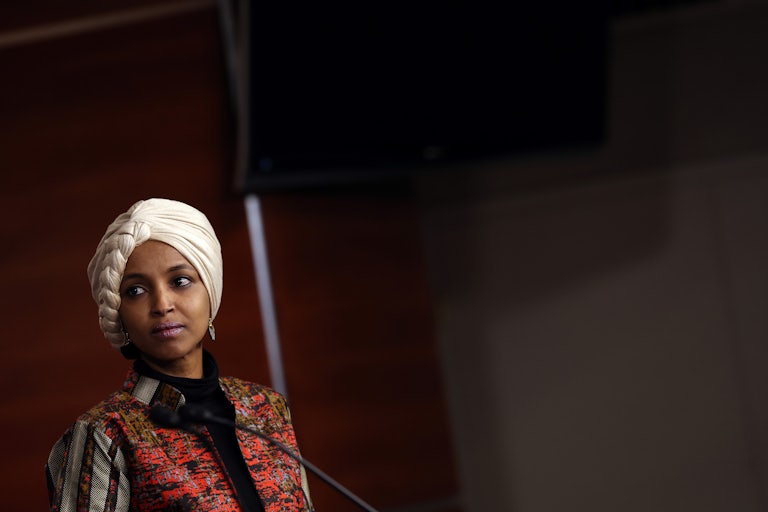 Ilhan Omar stands at a podium and looks to the side