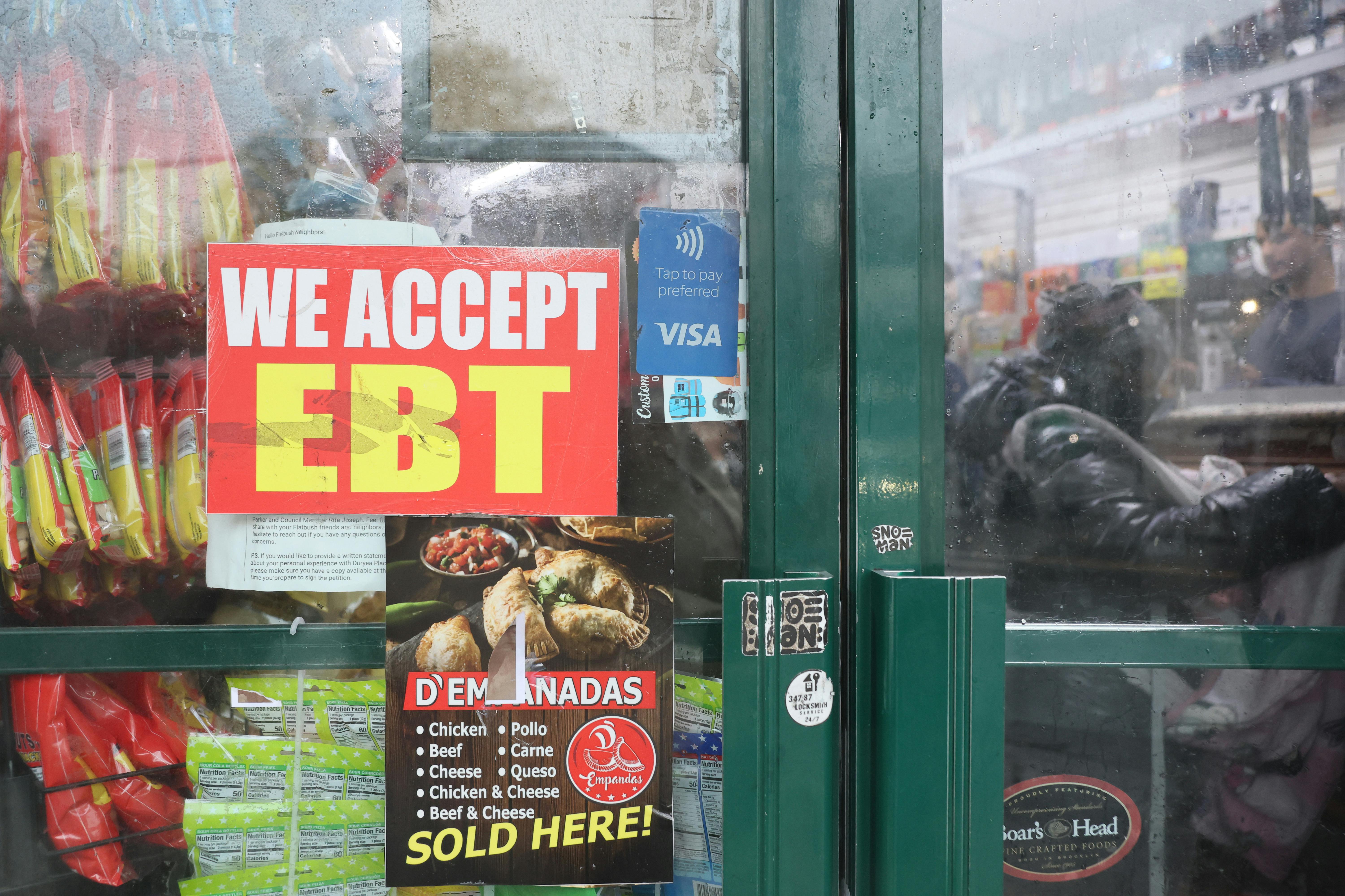 An EBT sign is displayed on the window of a grocery store.