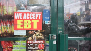 An EBT sign is displayed on the window of a grocery store.