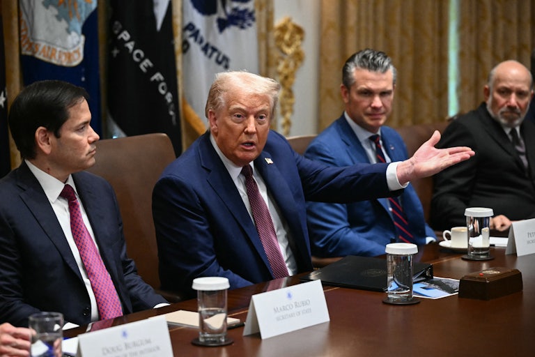 Donald Trump gestures and speaks while sitting in a Cabinet meeting