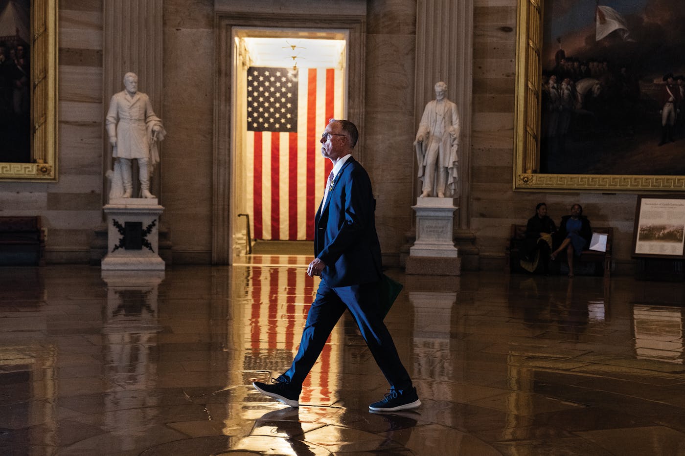 Democratic Representative Jared Huffman walks through the halls of Congress with an American flag in the background