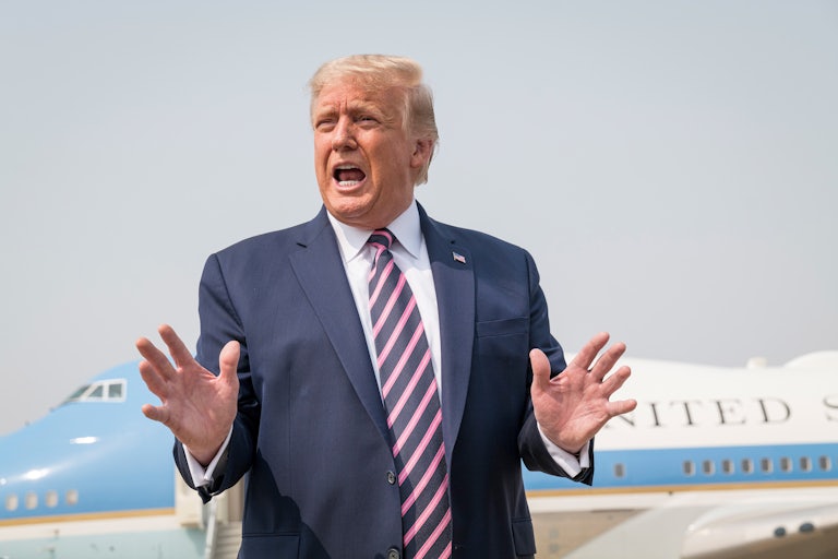 President Donald Trump stands on an airport tarmac while touring the California wildfire destruction.