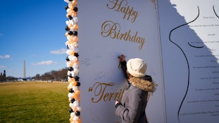 A woman signs a giant replica of Trump's birthday letter to Jeffrey Epstein on the National Mall in Washington, D.C.