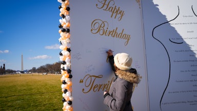 A woman signs a giant replica of Trump's birthday letter to Jeffrey Epstein on the National Mall in Washington, D.C.