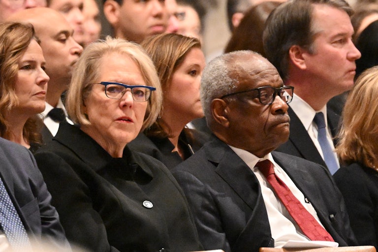 Ginni Thomas and Clarence Thomas seated in a crowd, side by side.