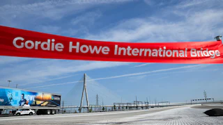 A large ribbon reading "Gordie Howe International Bridge" hangs over the empty bridge.