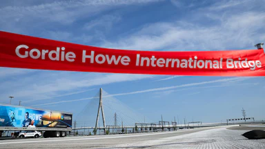 A large ribbon reading "Gordie Howe International Bridge" hangs over the empty bridge.