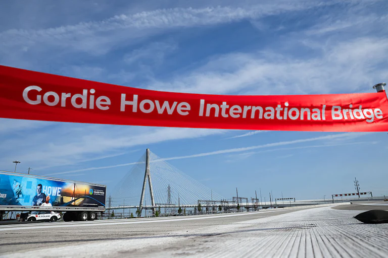 A large ribbon reading "Gordie Howe International Bridge" hangs over the empty bridge.