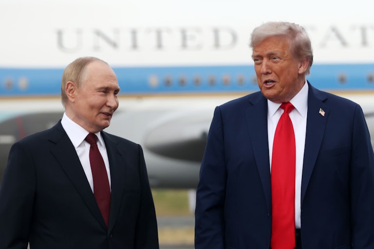 Vladimir Putin and Donald Trump speak while standing next to each other on an airport tarmac