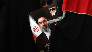 A demonstrator holds a picture of Iran’s new Supreme Leader Ayatollah Mojtaba Khamenei. The poster includes smaller photos of Ali Khamenei and Ruhollah Khomeini.