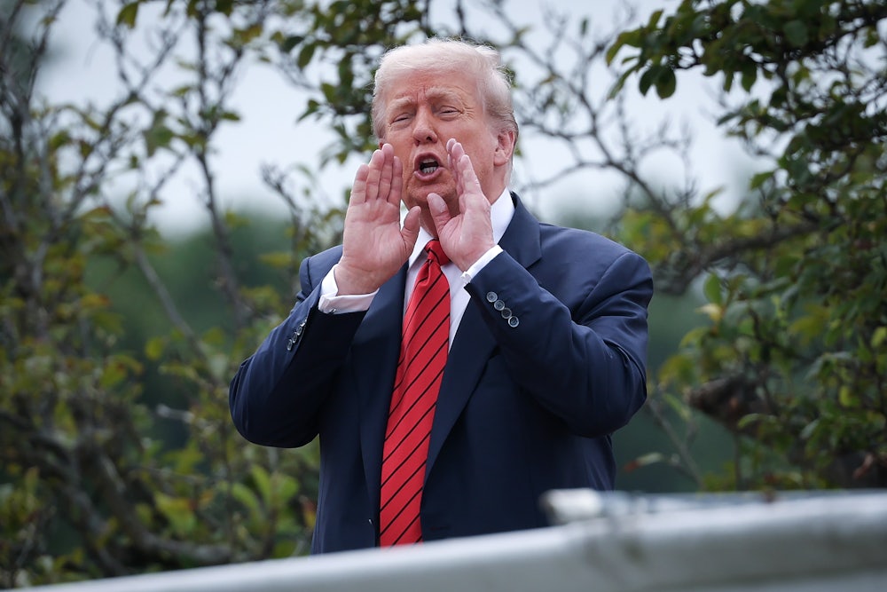 Donald Trump puts his hands next to his mouth and speaks while standing on the White House roof
