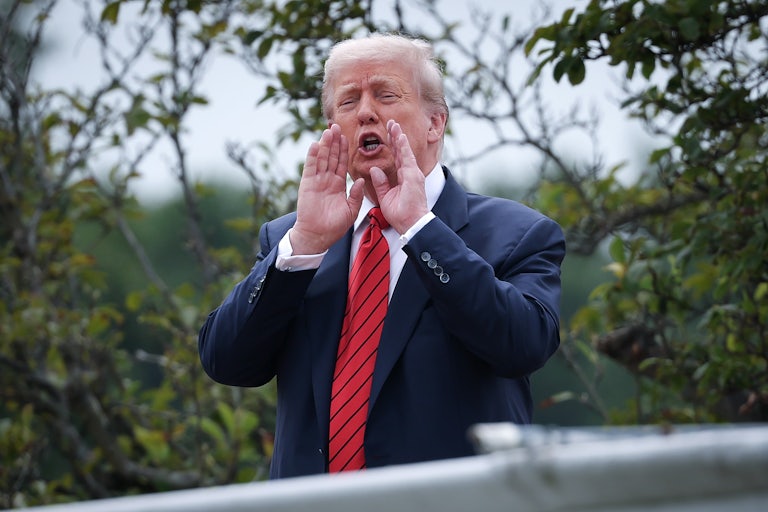 Donald Trump puts his hands next to his mouth and speaks while standing on the White House roof