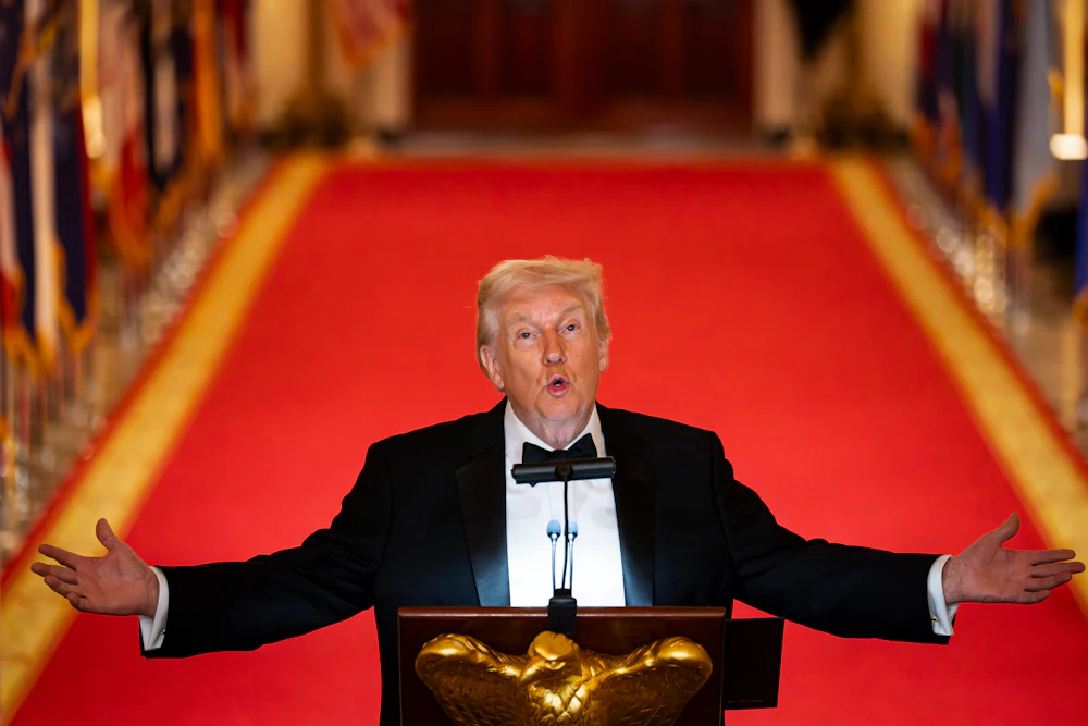 Donald Trump holds his arms out to the side and looks up while speaking at a podium