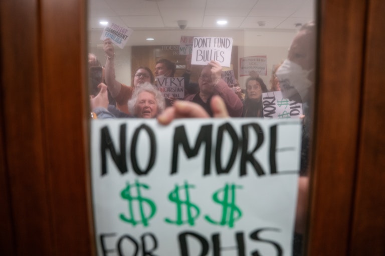 A person holds a sign that says, "No more $$$ for DHS" up to a window during an anti-ICE protest in Nashville, Tennessee