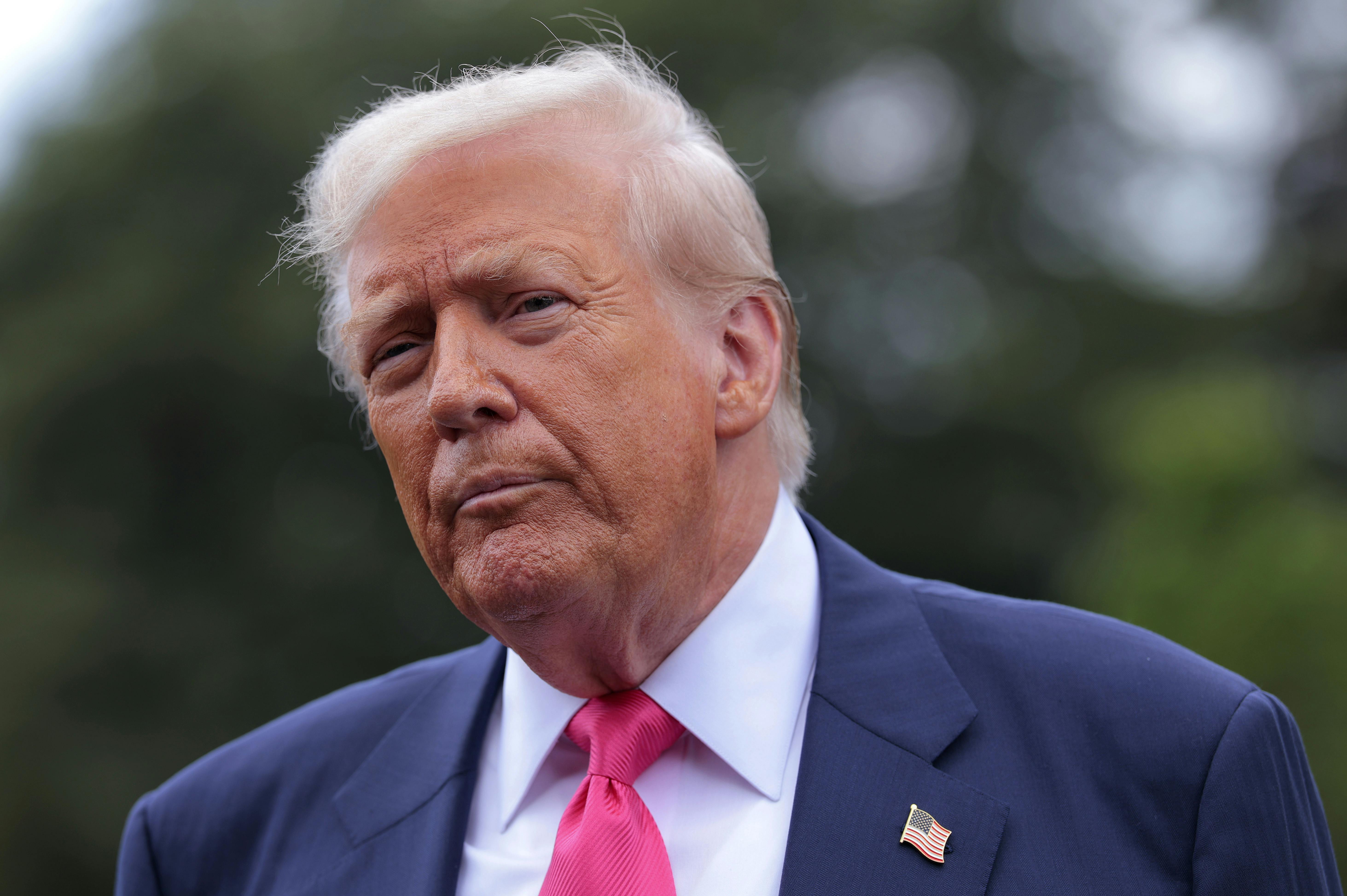 Donald Trump purses his lips as he walks outside the White House 