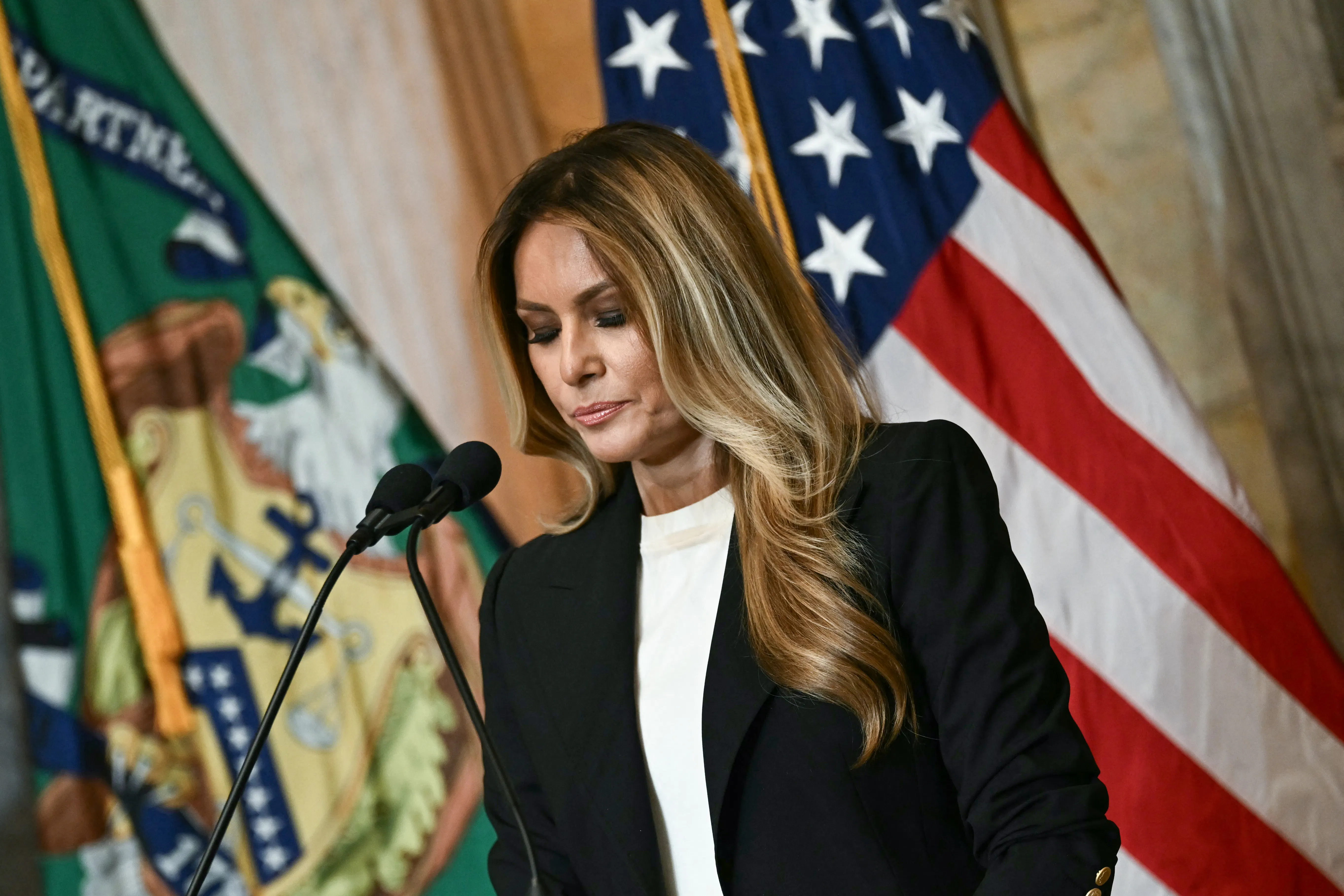 Melania Trump looks down while standing at a podium