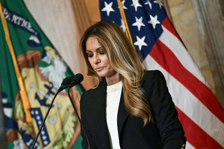 Melania Trump looks down while standing at a podium