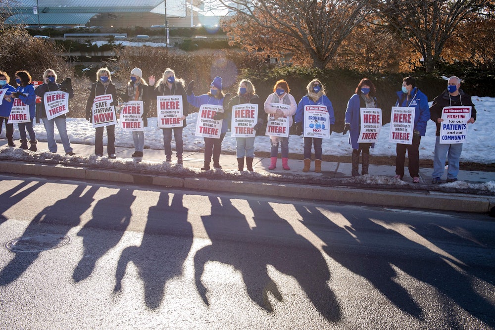 Nurses and supporters stand in a picket line with signs