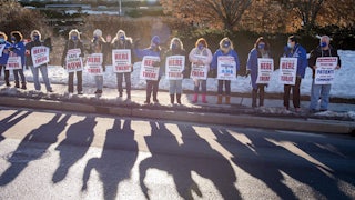 Nurses and supporters stand in a picket line with signs