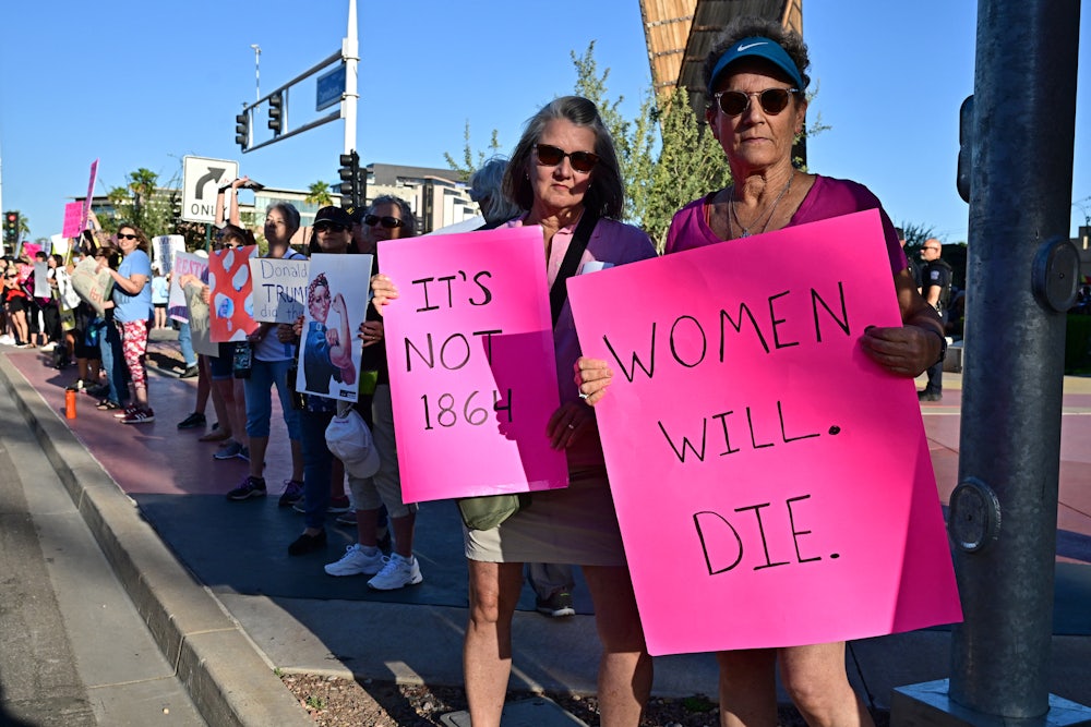 Demonstrators hold signs, including one reading "women will die."