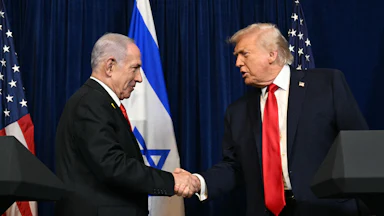 Israeli Prime Minister Benjamin Netanyahu and Donald Trump shake hands while standing at podiums during an event