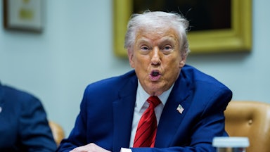 Donald Trump speaks while sitting at a table
