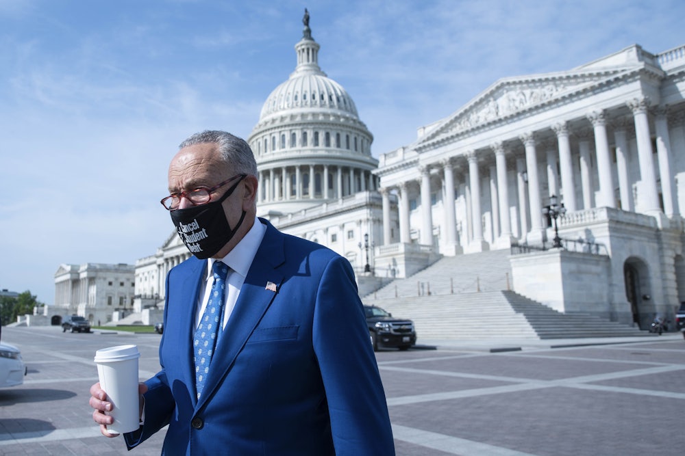 Sen. Chuck Schumer arrives with a cup of coffee to a news conference on the Capitol grounds.