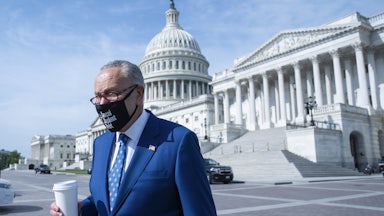 Sen. Chuck Schumer arrives with a cup of coffee to a news conference on the Capitol grounds.