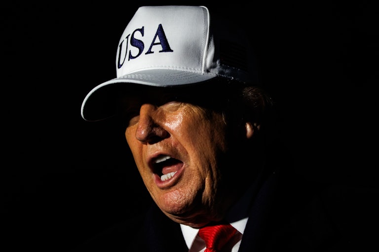 Donald Trump speaks while wearing a white USA hat