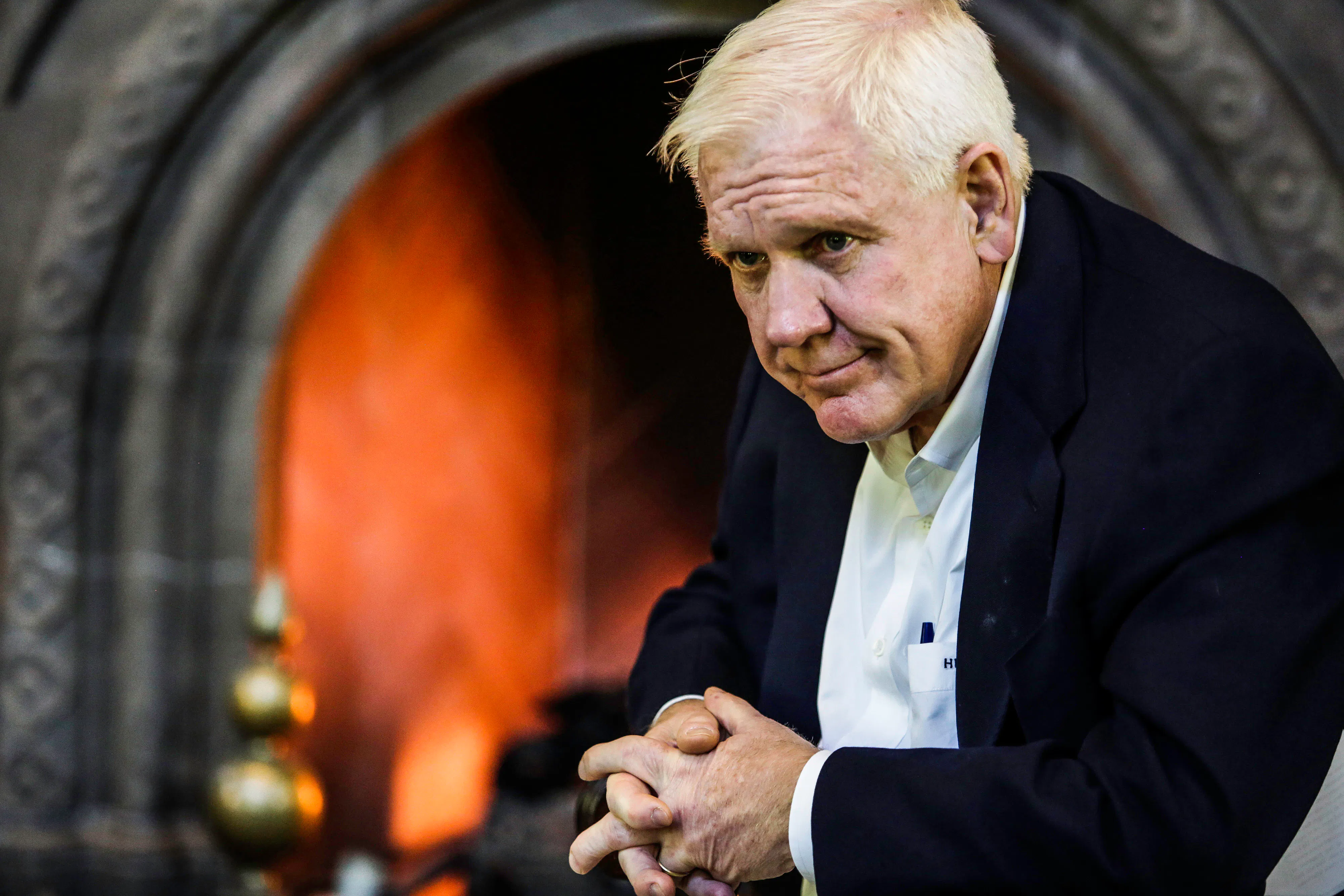 Harlan Crow sits with his hands folded in front of him