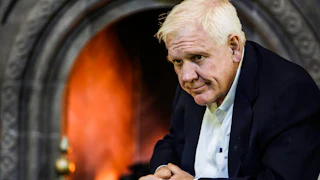 Harlan Crow sits with his hands folded in front of him