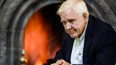 Harlan Crow sits with his hands folded in front of him