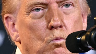 Donald Trump purses his lips while standing at a microphone