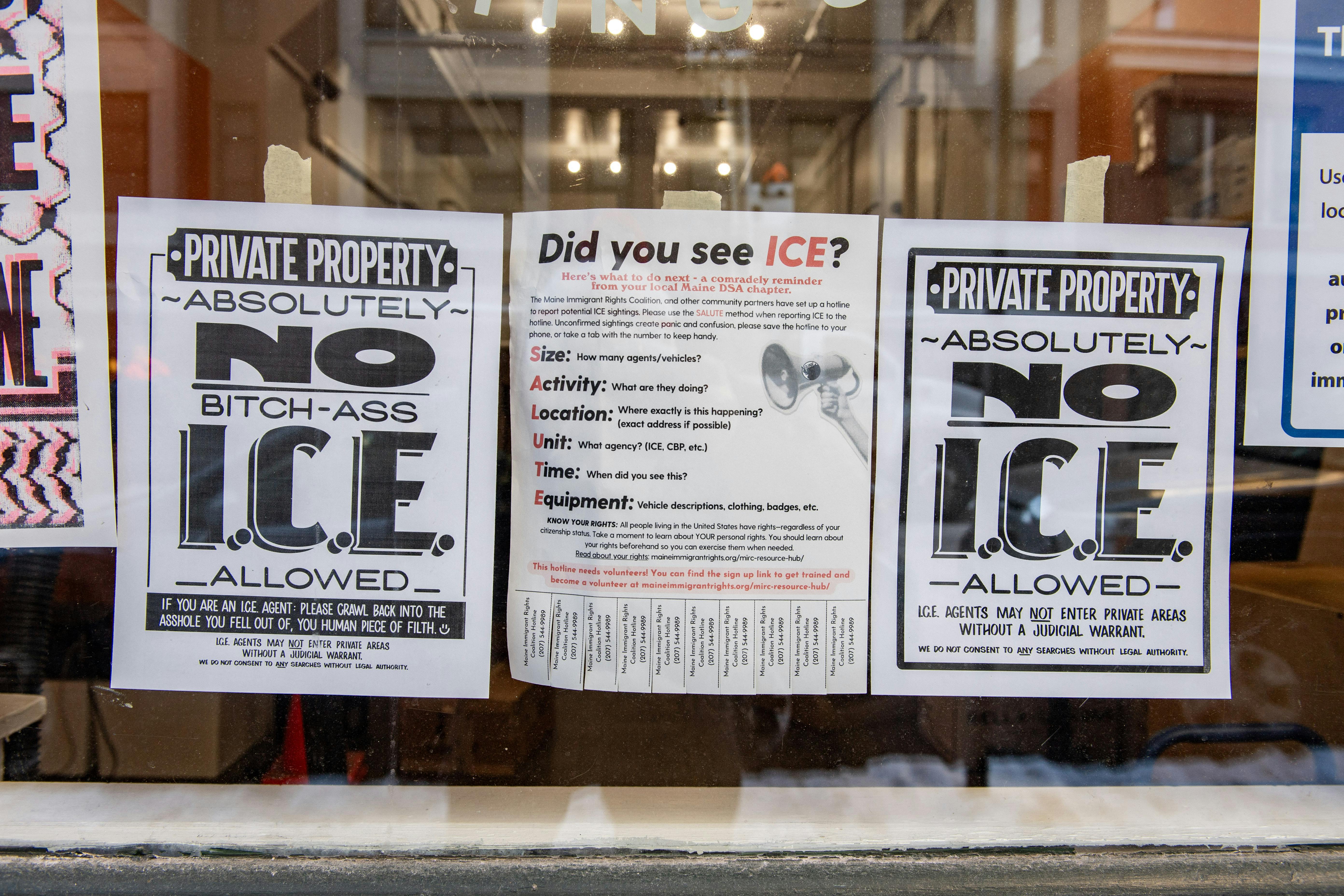 Anti-ICE signs hang in the window of a business in Portland, Maine