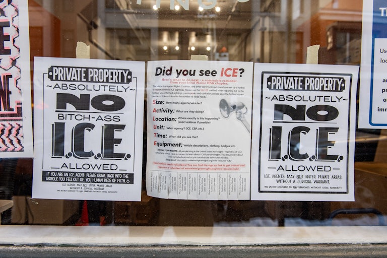 Anti-ICE signs hang in the window of a business in Portland, Maine.