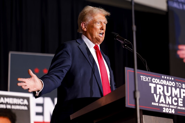 Donald Trump holds his arms out to the side while speaking at a campaign event