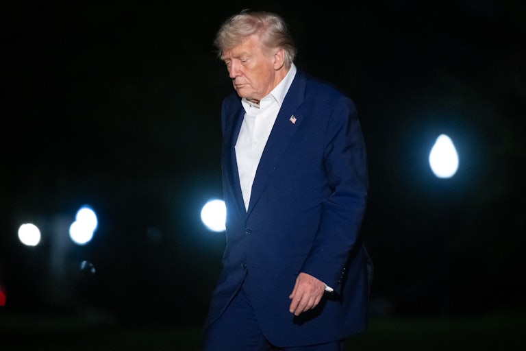 Donald Trump looks down while walking outside the White House