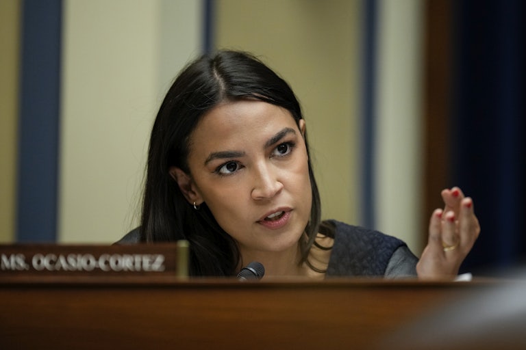 Representative Alexandria Ocasio-Cortez speaks and makes a hand gesture during a congressional hearing.