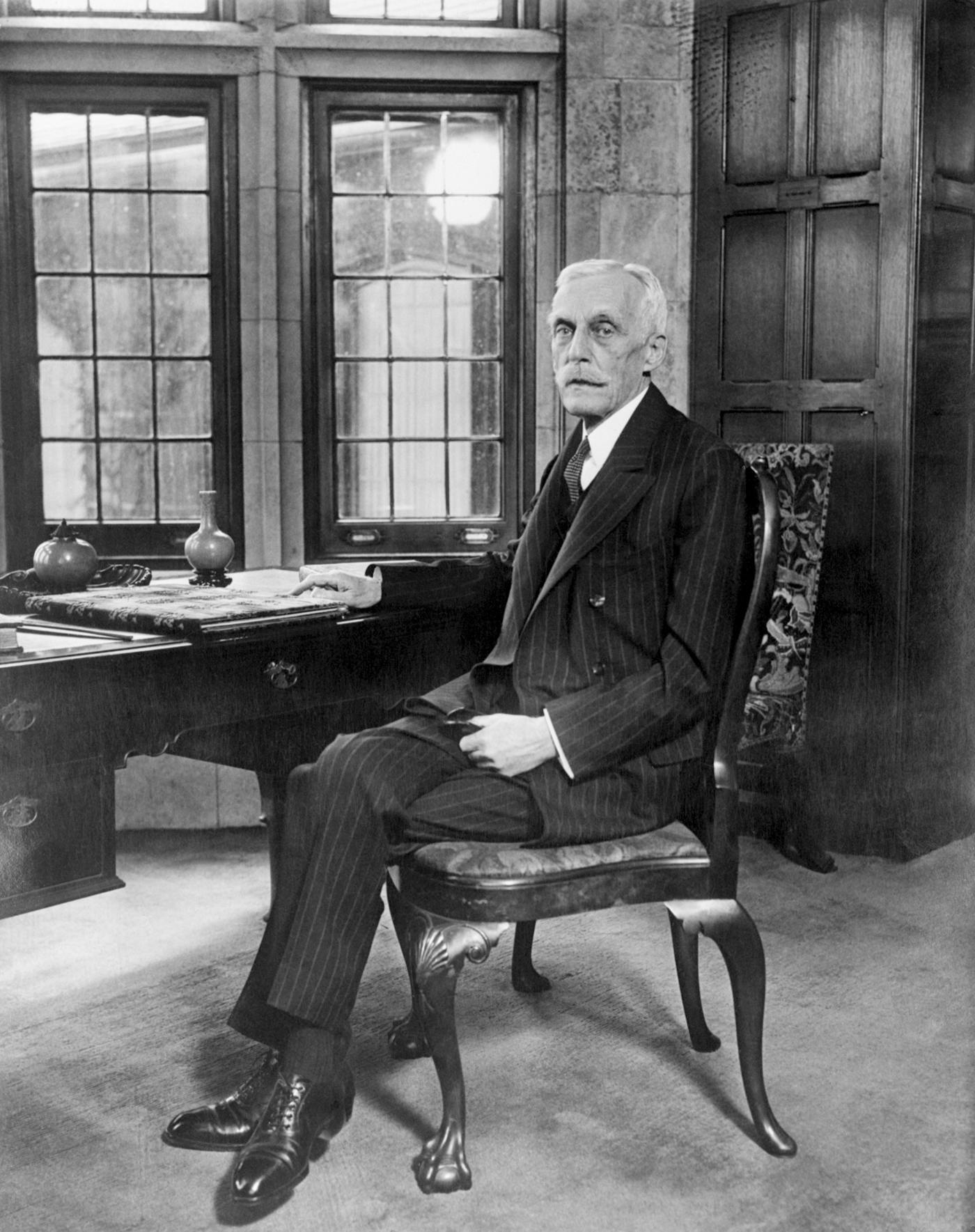 A photograph from the 1920s of Secretary of the Treasury Andrew Mellon sitting in a chair at his desk. His income more than doubled while he was in office.