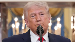 Donald Trump frowns while standing at a microphone