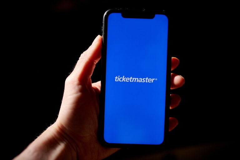 A hand holds a phone that reads "Ticketmaster"