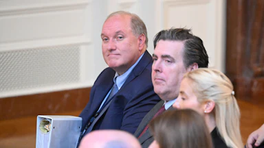 John Solomon holds a biner and appears to zone out while seated.